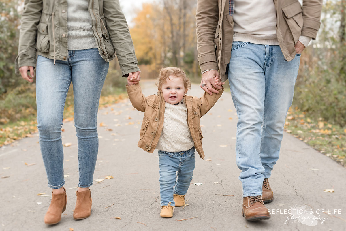 father and mother walking and holding childs hands