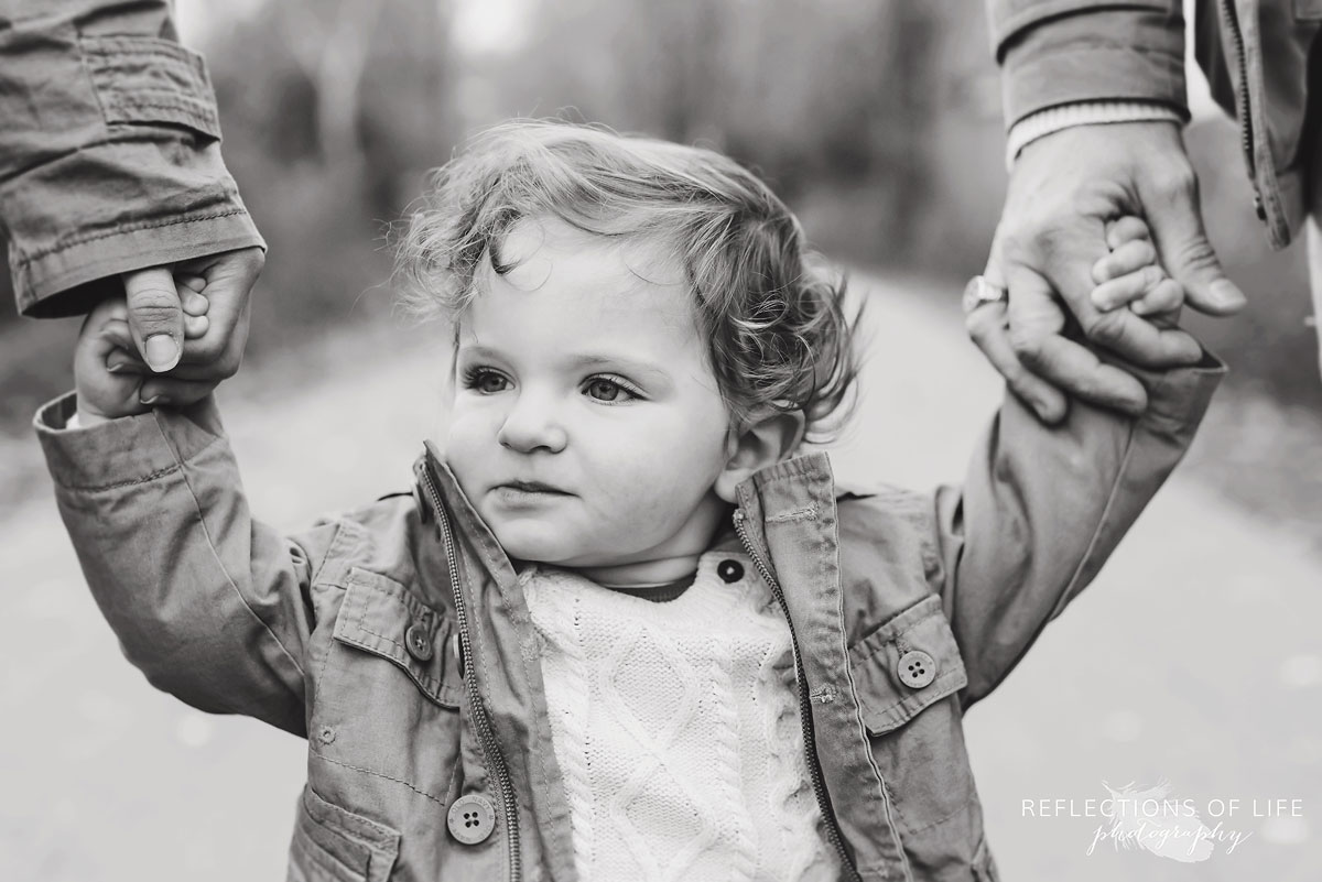 child holding mom and dads hands