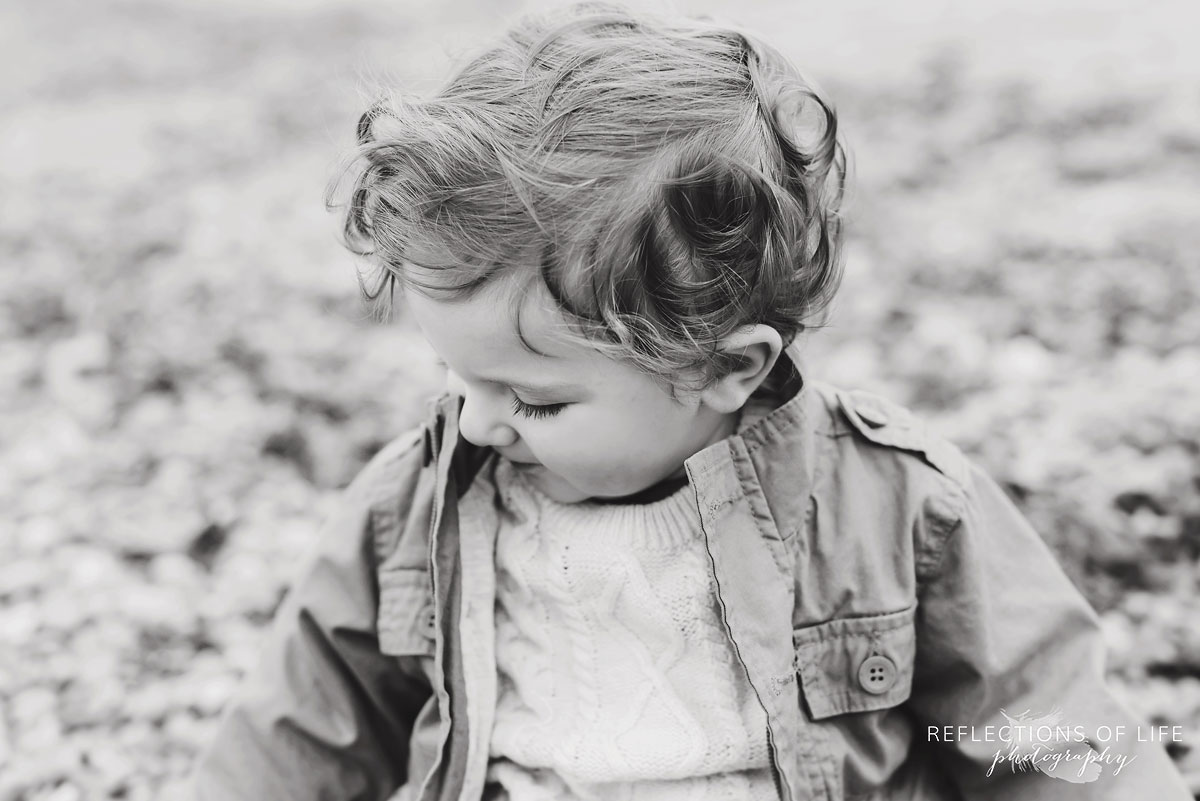 black and white of child sitting on beach