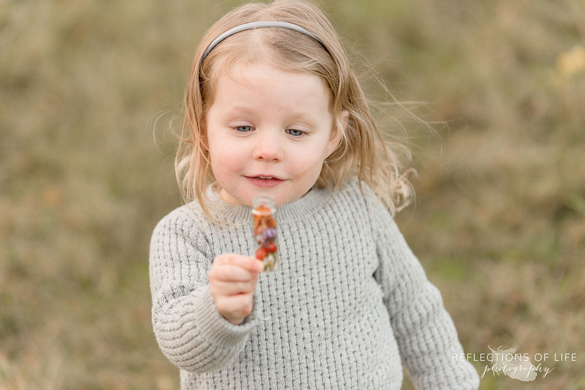 little girl looking at flowers in mini jar