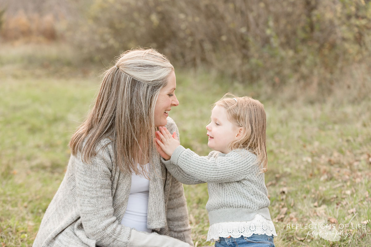 young girl holding mamas face