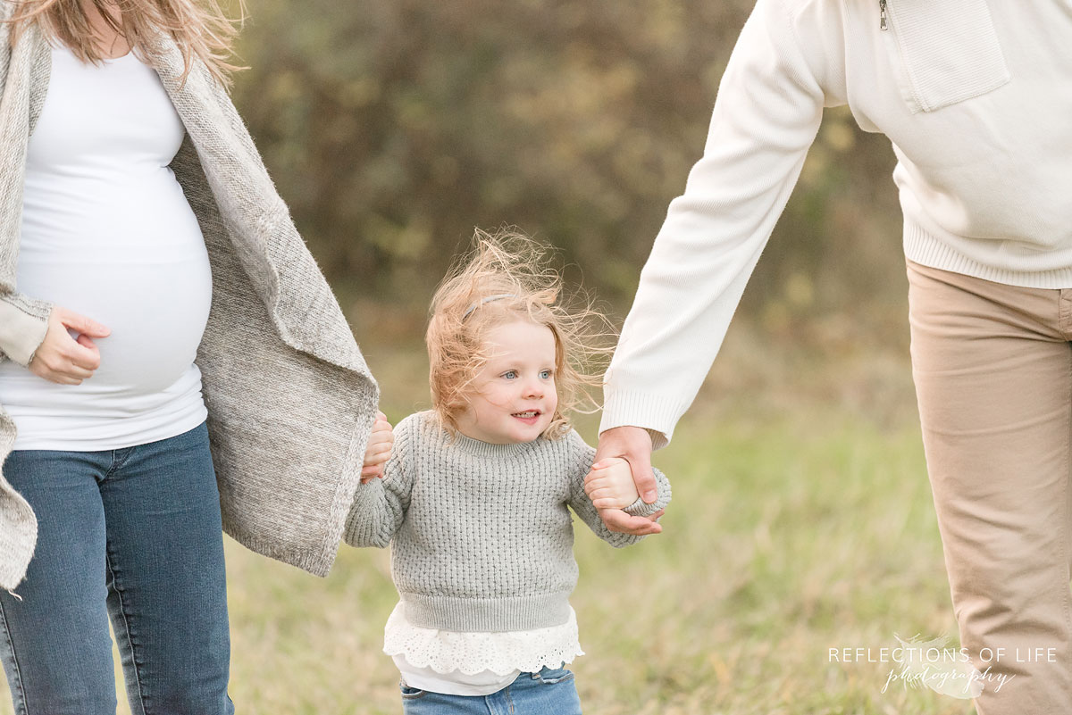 little girl holding her parents hand in cold fall weather