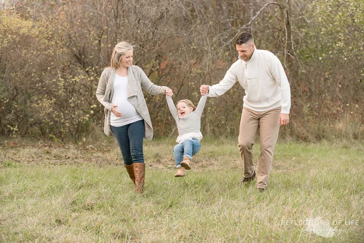 mom and dad swinging daughter with arms