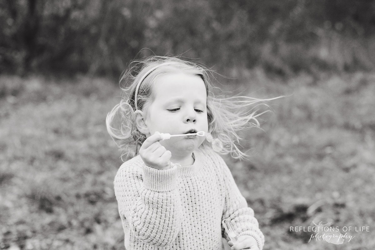 little girl blowing bubbles outdoors