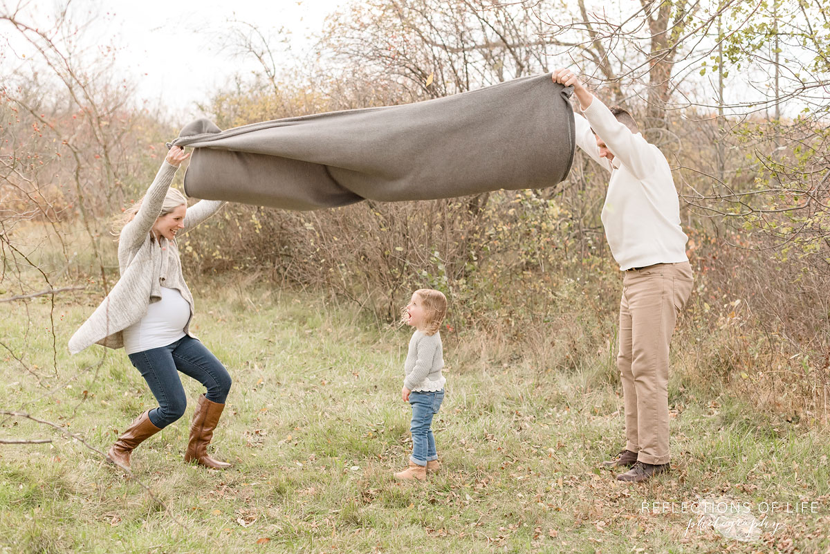 parents holding blanket over little daughter