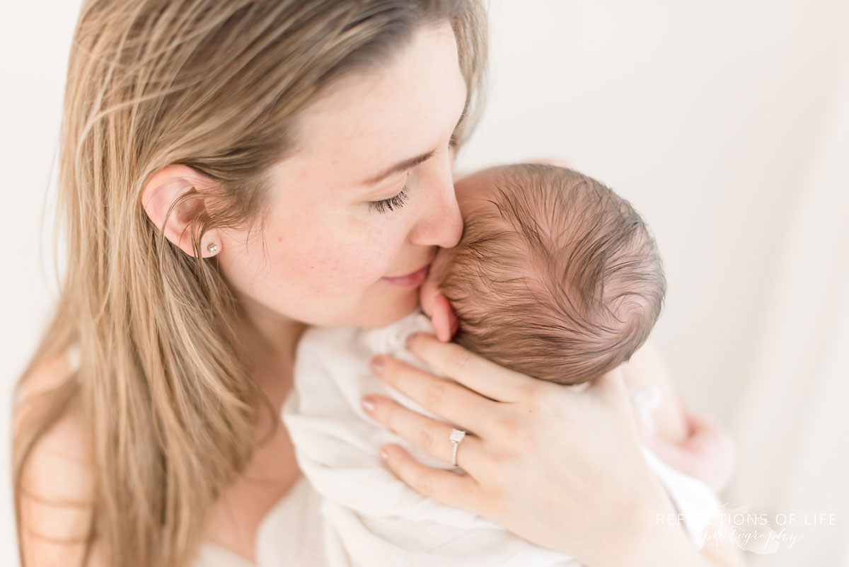 mama holding her newborn close in white studio