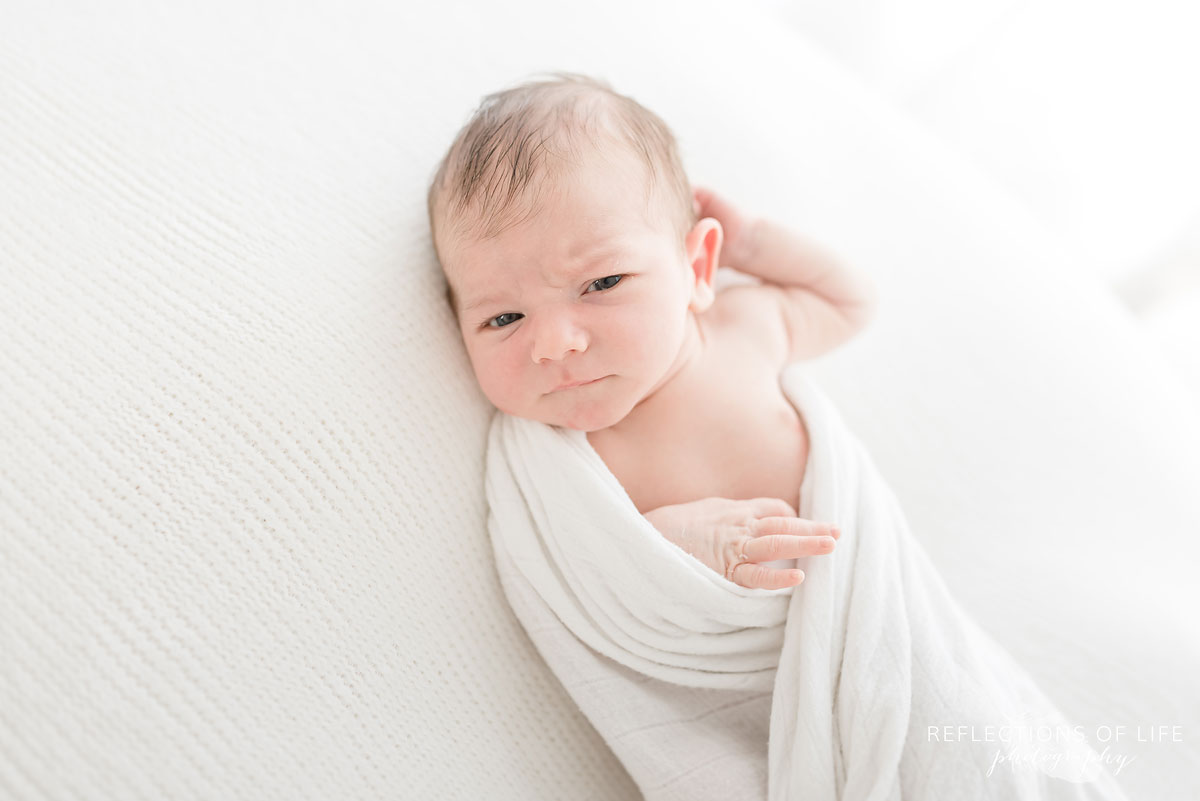 newborn baby sitting in white studio