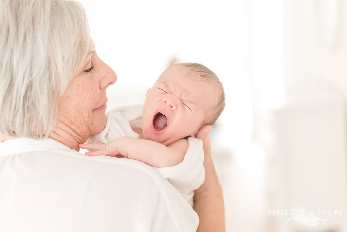 grandma holding newborn yawning