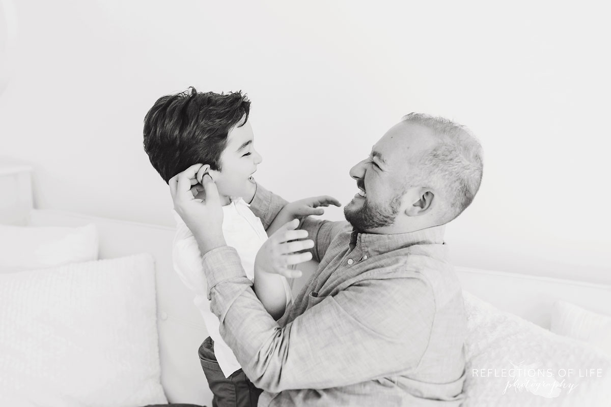 father and son playing in white studio
