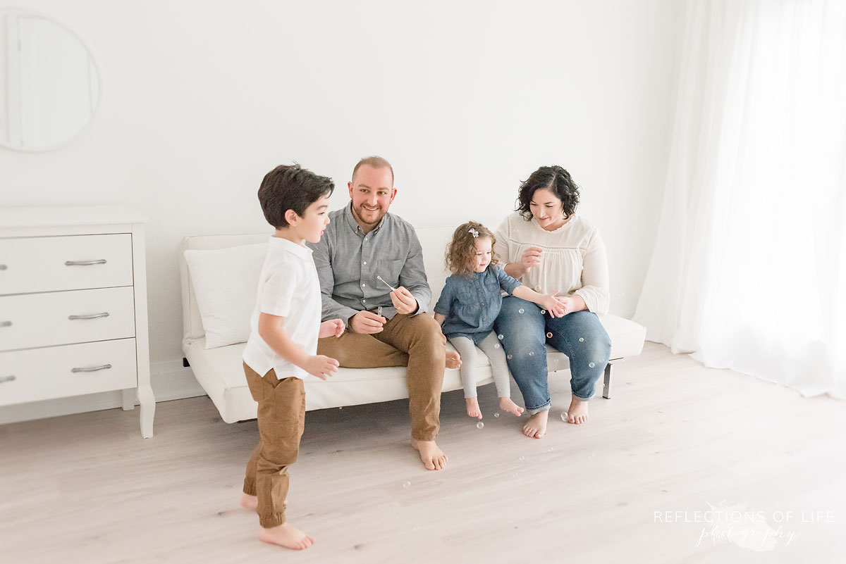 family blowing bubbles in white studio
