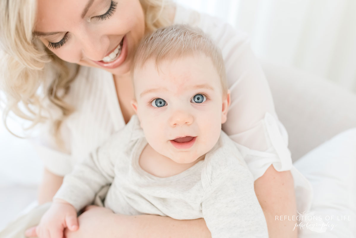 Copy of Copy of baby boy smiling at the camera while in his mother's arms