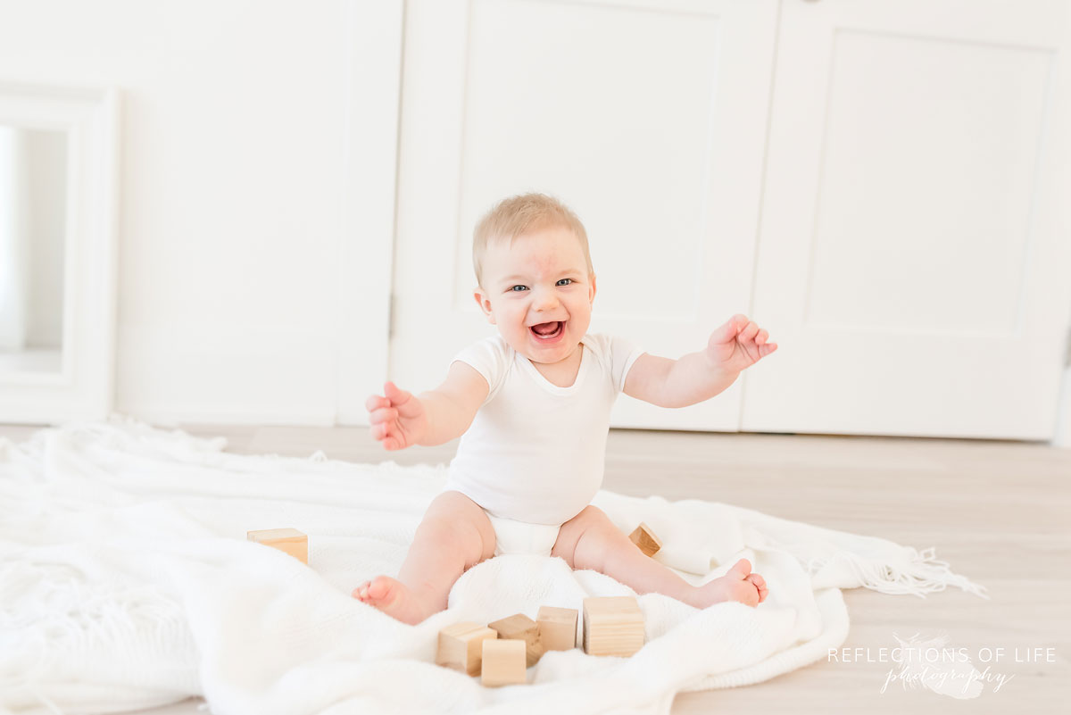 Copy of Copy of Baby boy laughing at the camera and playing with wood blocks