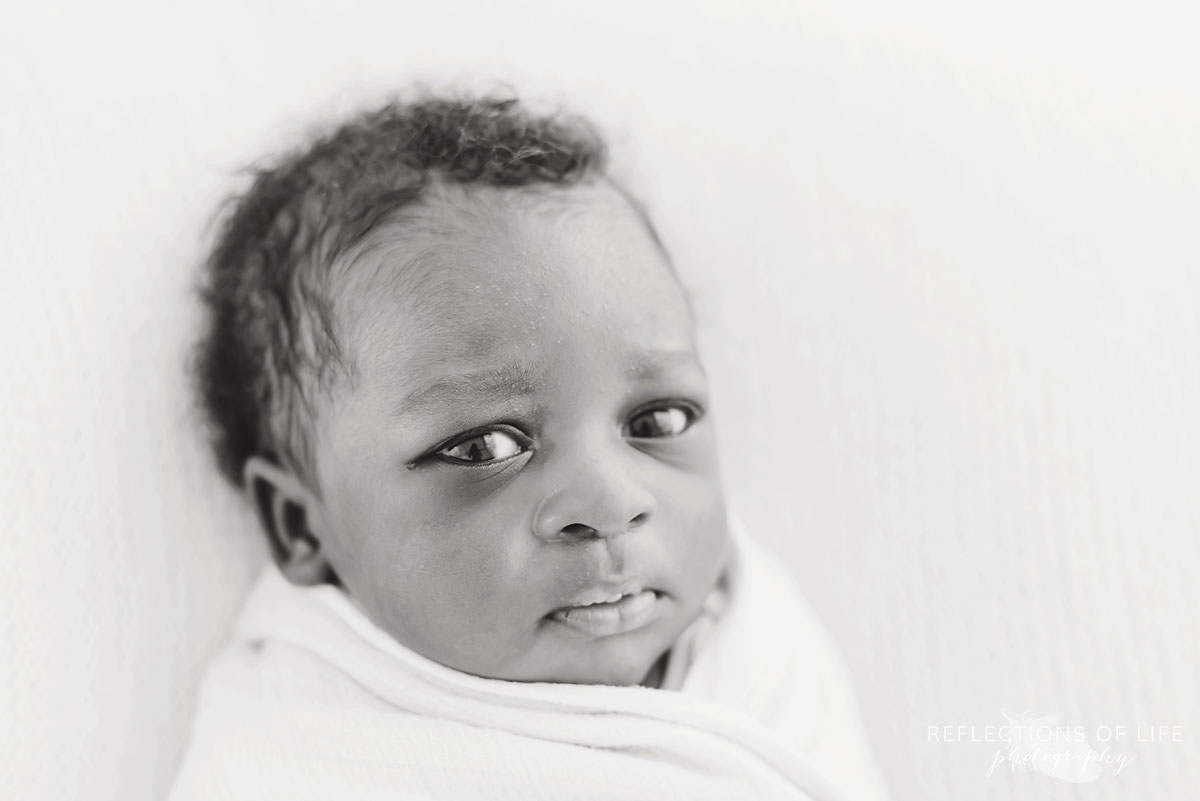 Adorable black and white of newborn baby looking into the camera