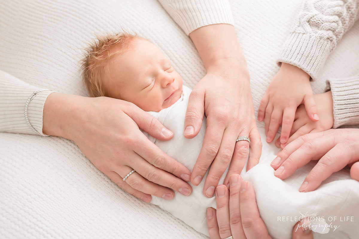 Newborn portrait of family placing hands on their brand new baby.jpg