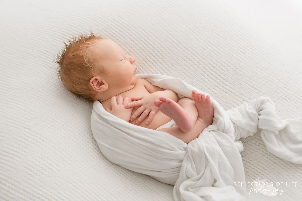 newbrn baby boy wrapped in Little Unicorn swaddle blacket.jpg
