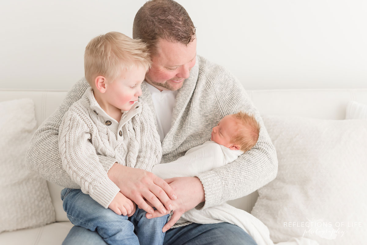 Daddy holding his newborn baby boy and older son.jpg