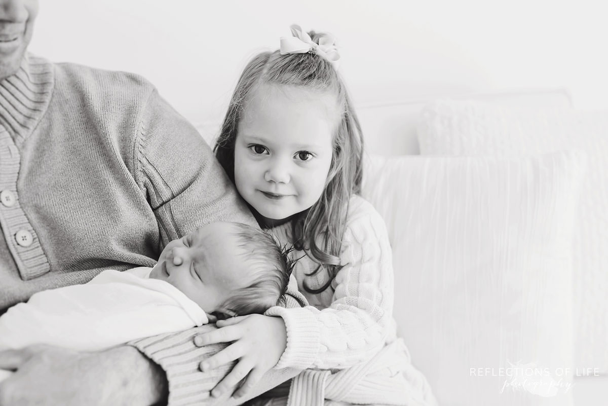 Cute little girl next to new born baby black and white