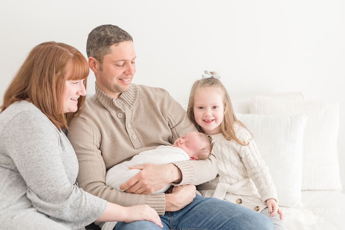 Family of four looks at newborn