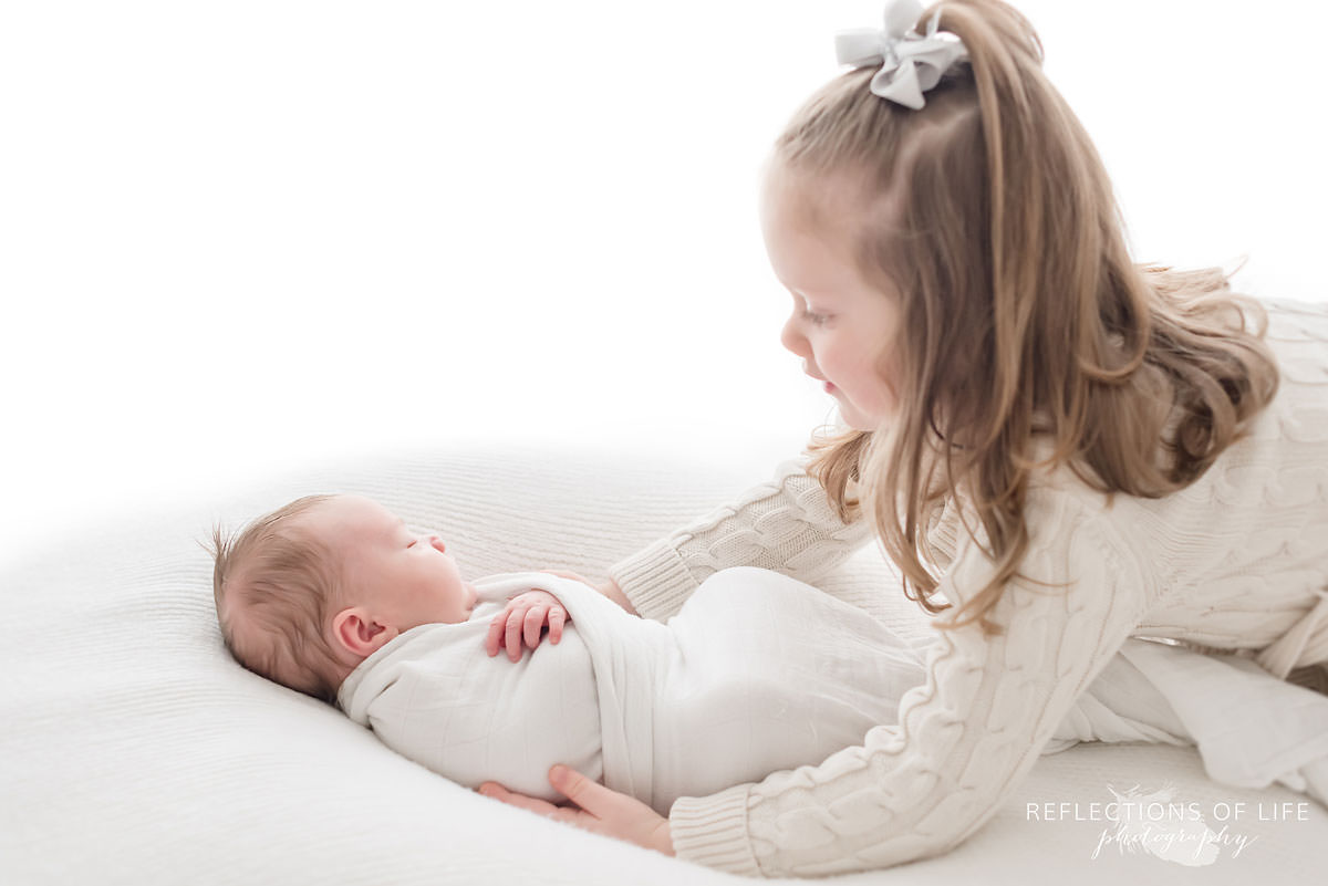 two siblings sister holds baby