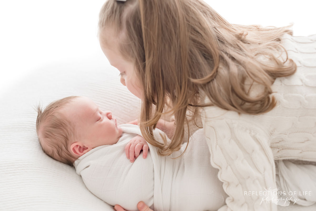 two siblings sister holds baby 