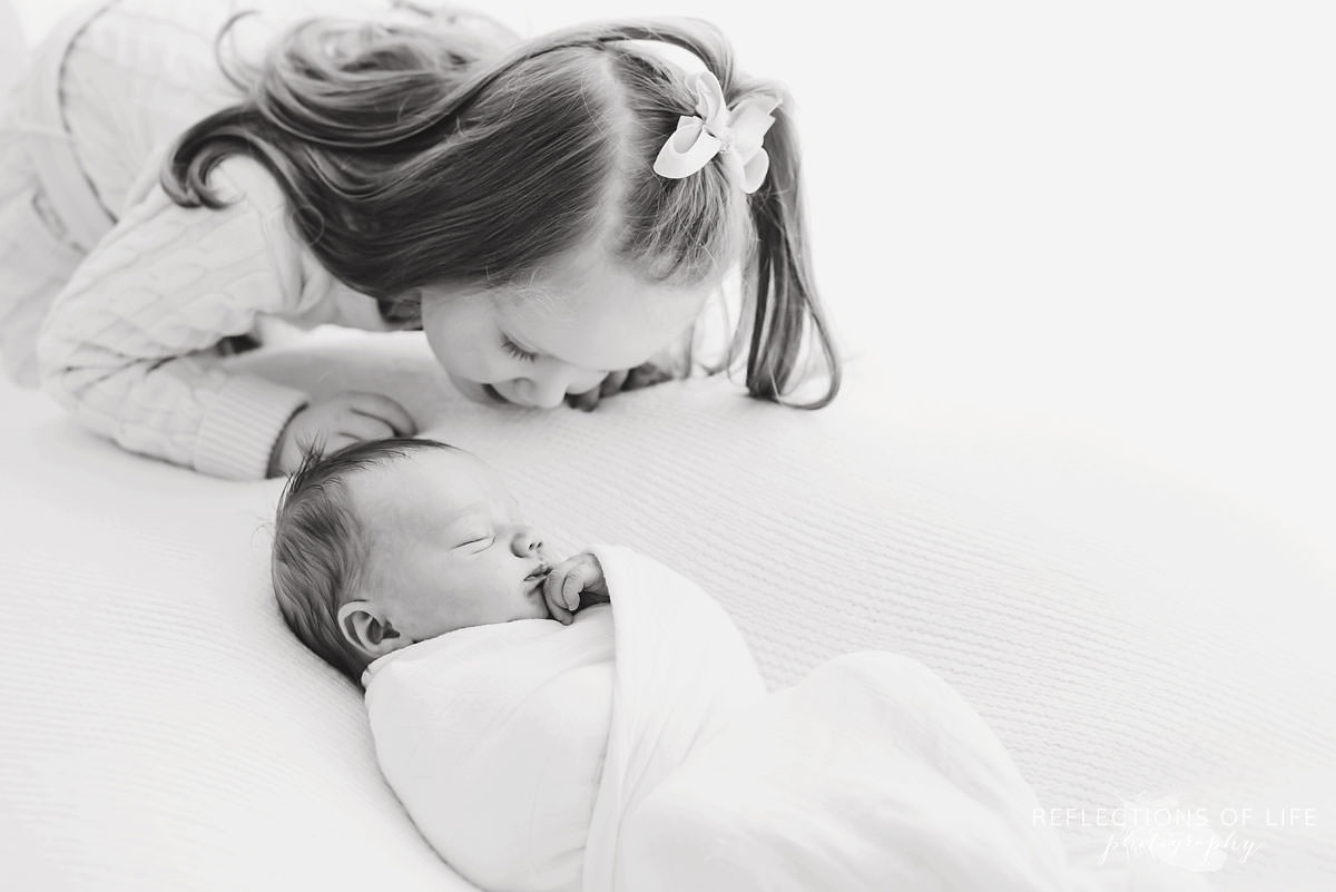 two siblings sister watches over baby sleeping black and white