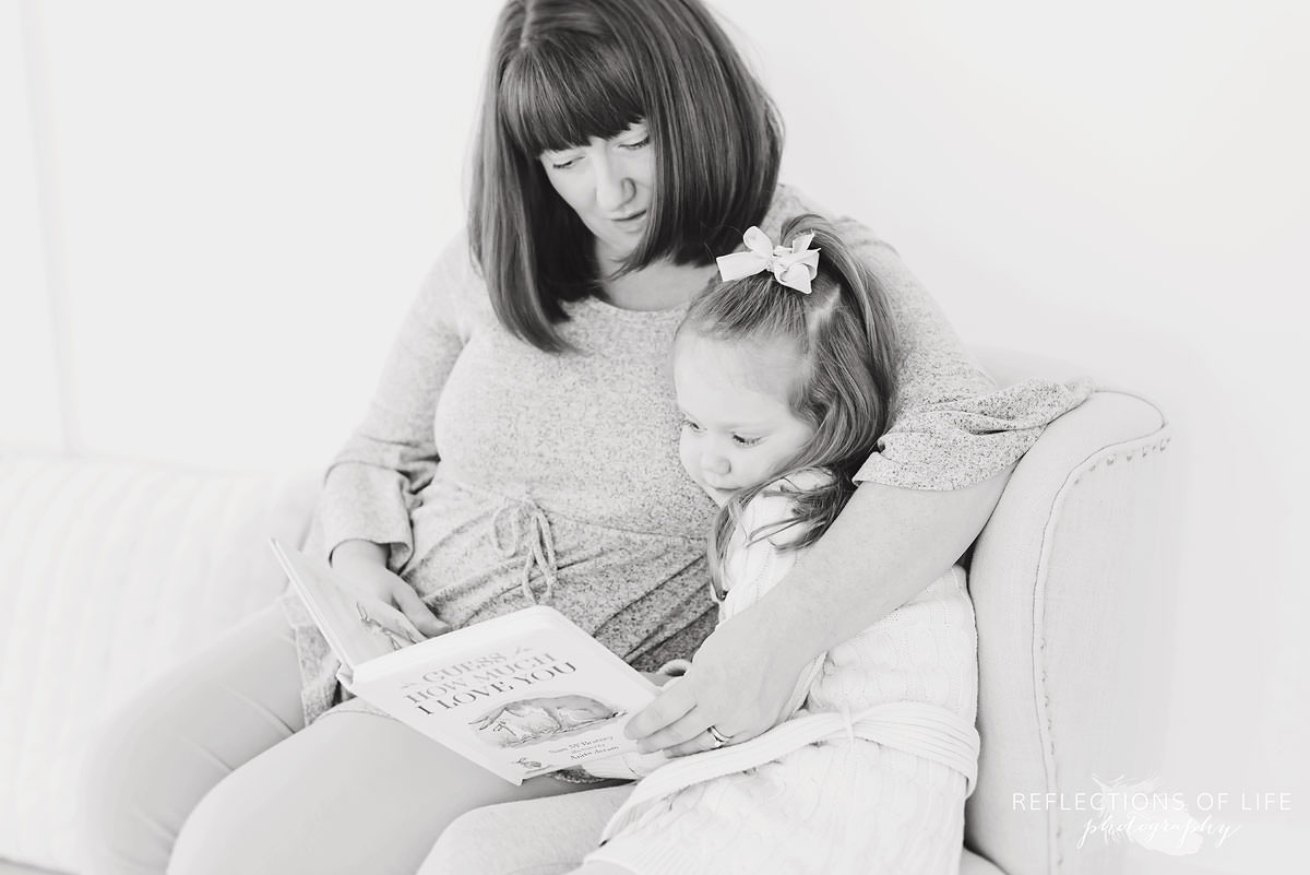 Mother and daughter read a book together in black and white