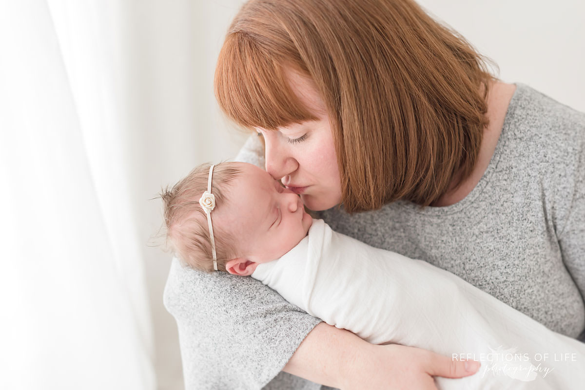 mother kisses childs head in natural light studio