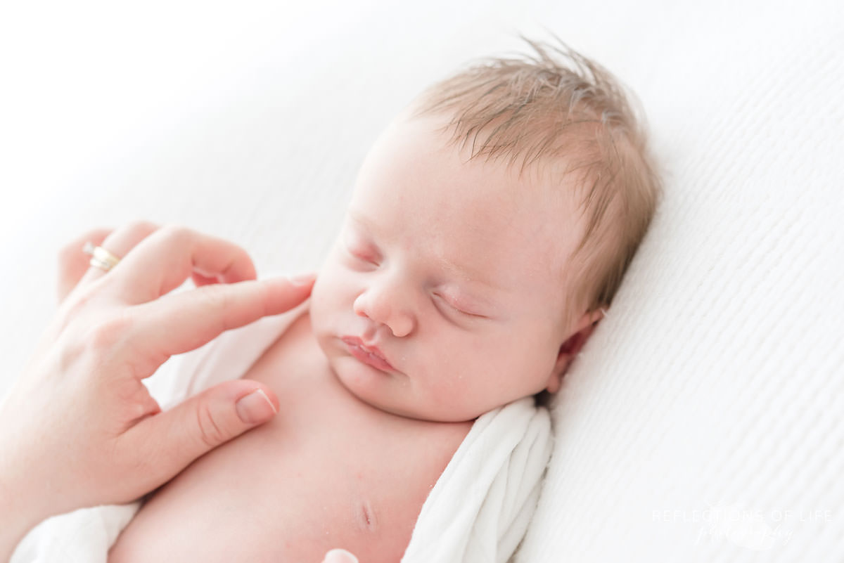 Mother touches sleeping baby's face with her finger