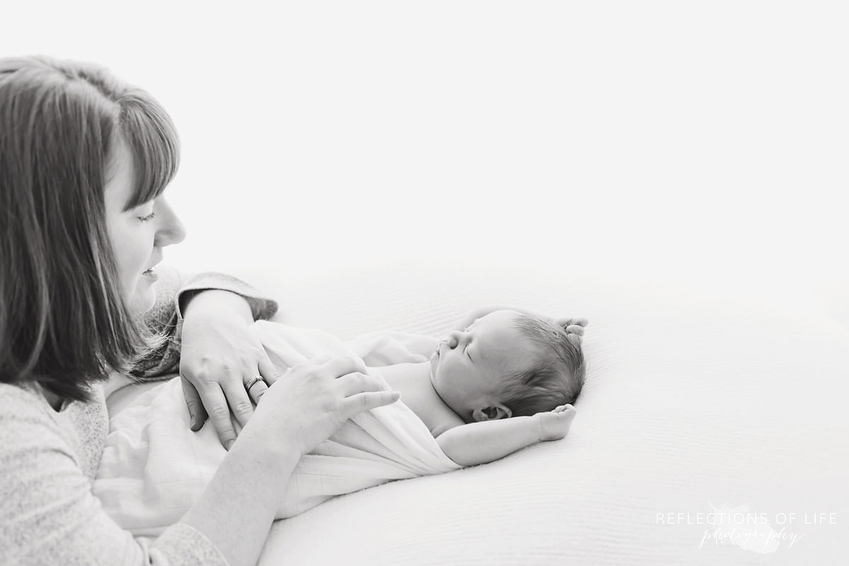 Mother lays on baby as they wake up in black and white