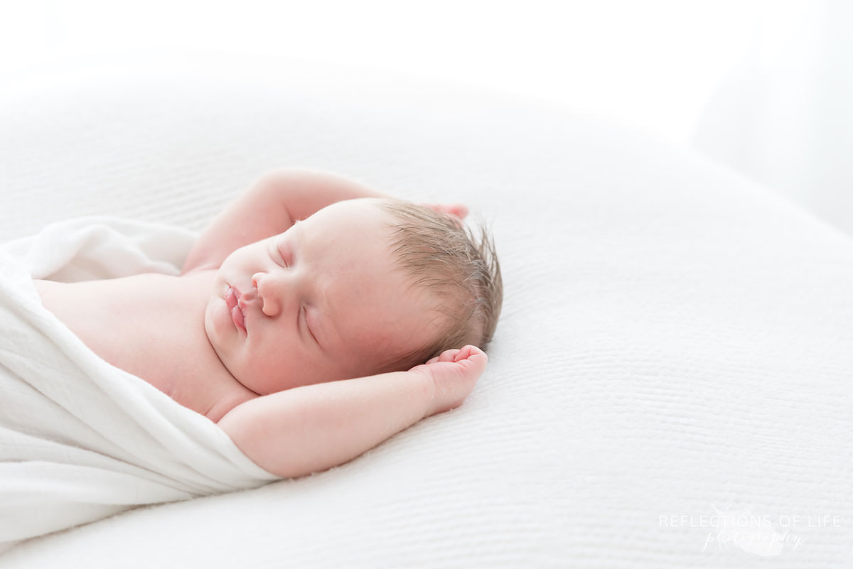 Baby sleeping with it's arms up in Ontario