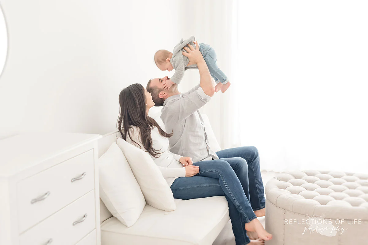 baby holds dads face in natural light studio.jpg