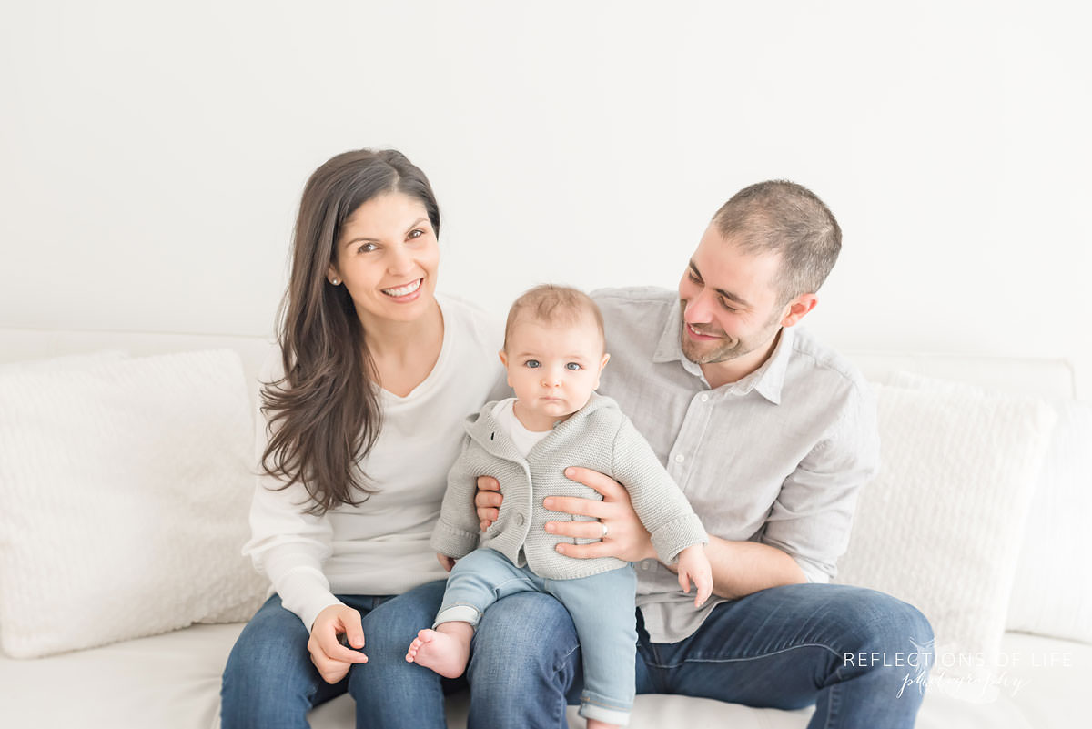 family of three smiles while father looks at son