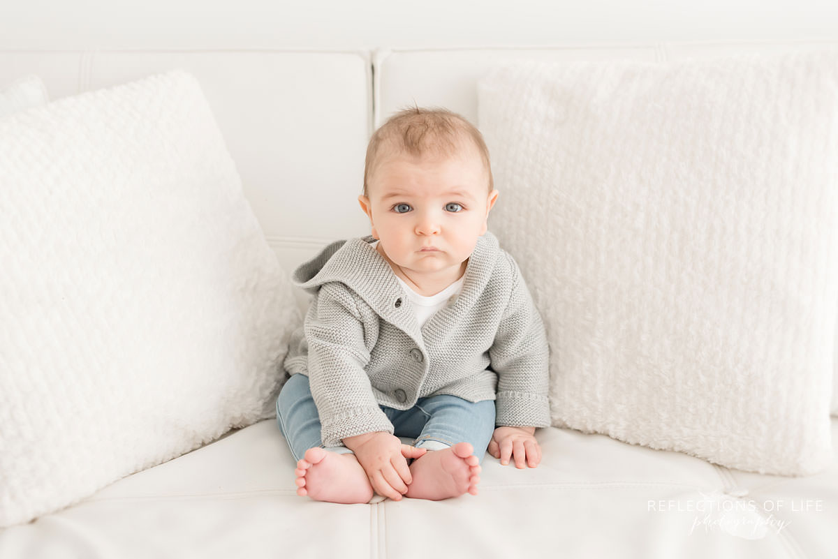 baby sits on couch looking at the camera in grimsby