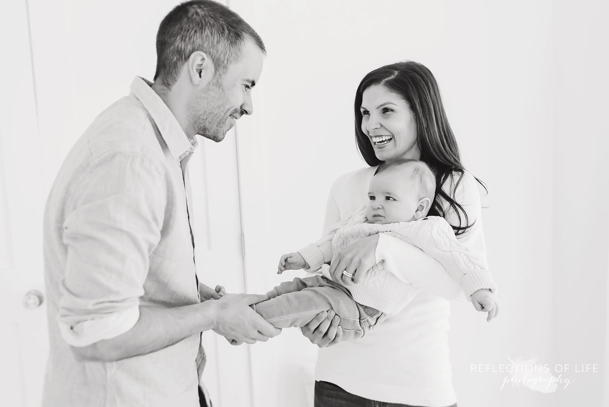 dad holds baby's feet as mother laughs in black and white