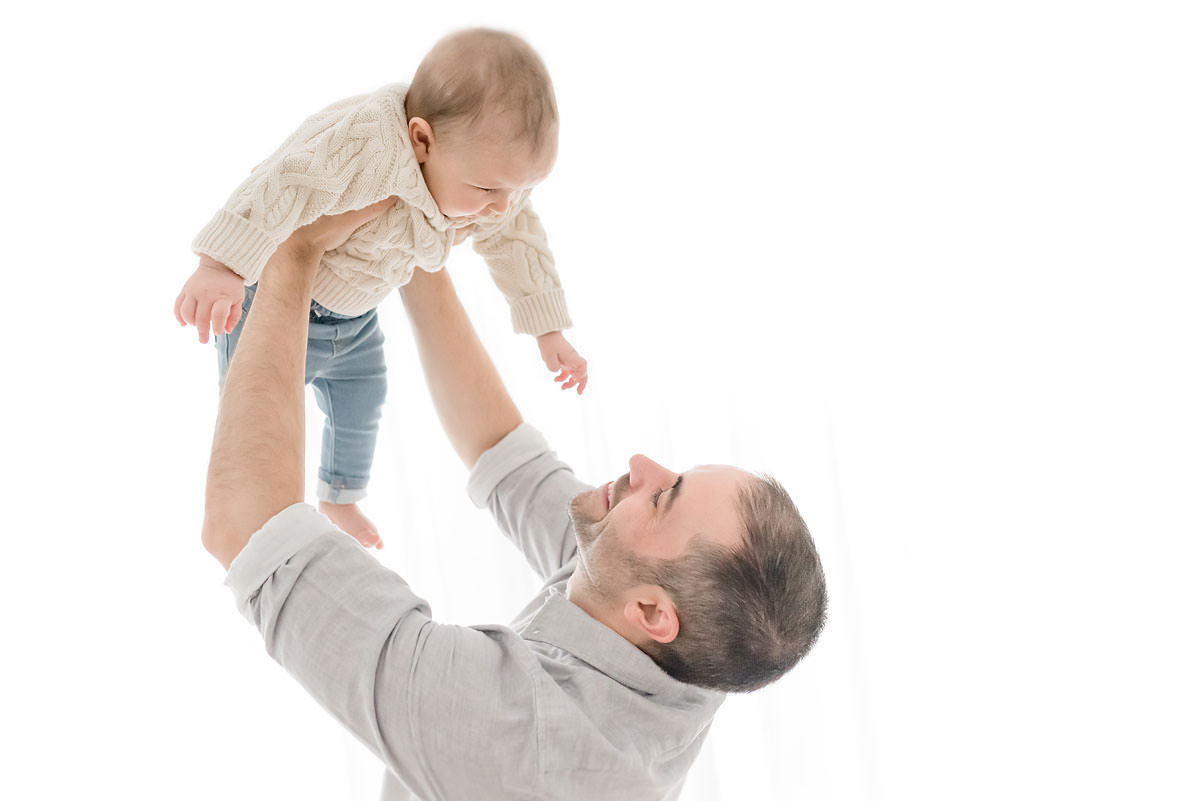 father lifts baby up as he reaches for his face in ontario