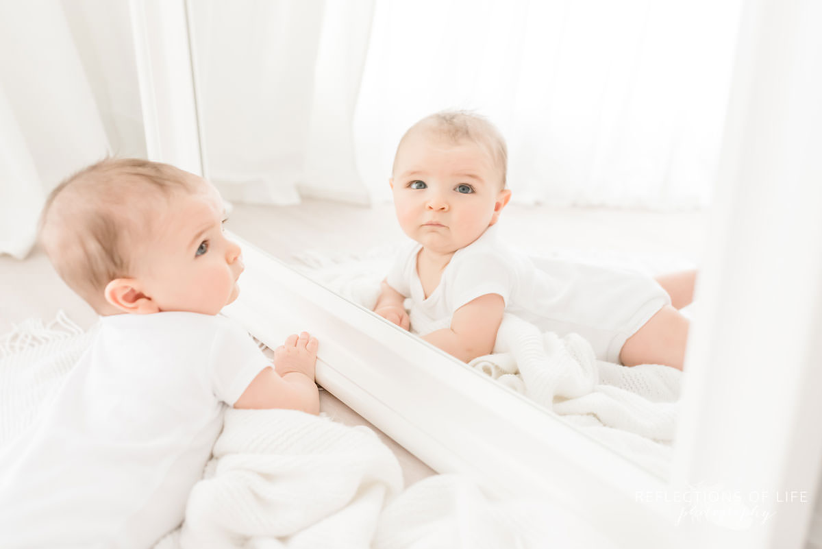 baby looks at camera through mirror in natural light studio