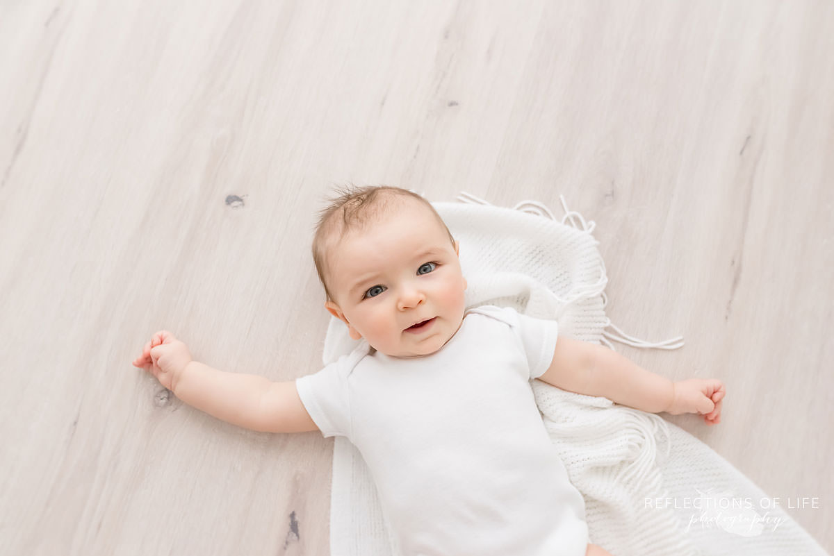 baby lays on blanket in natural light studio