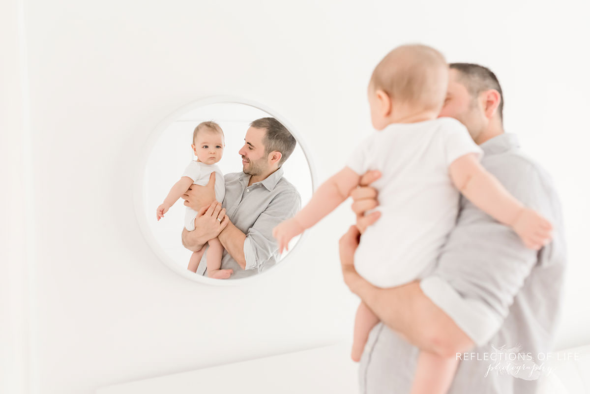 father holds son so he can see his reflection