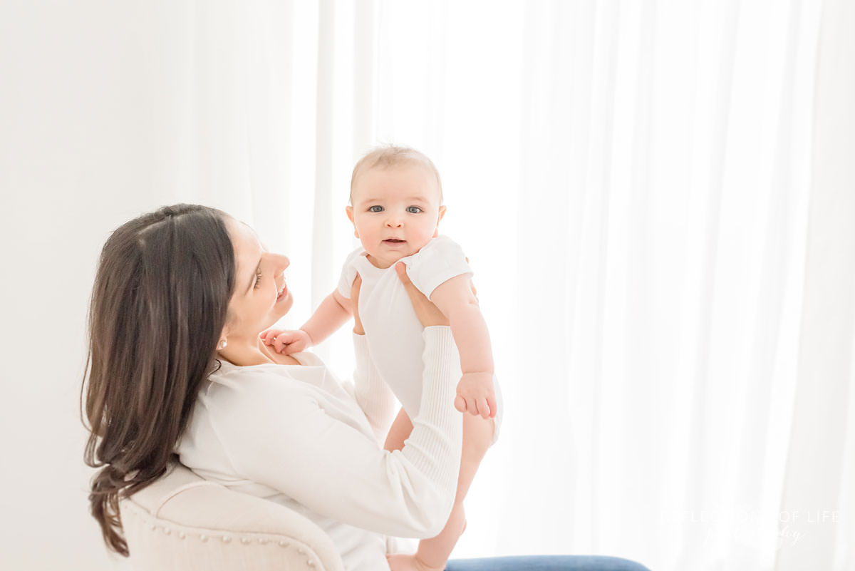 mother holds baby up as baby looks forward in ontario