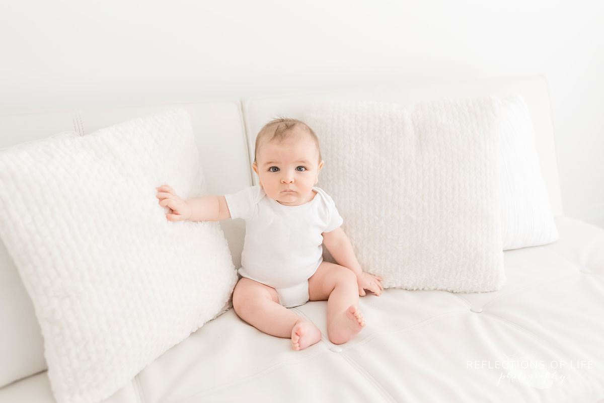 baby lays on pillows with his hand on one in ontario