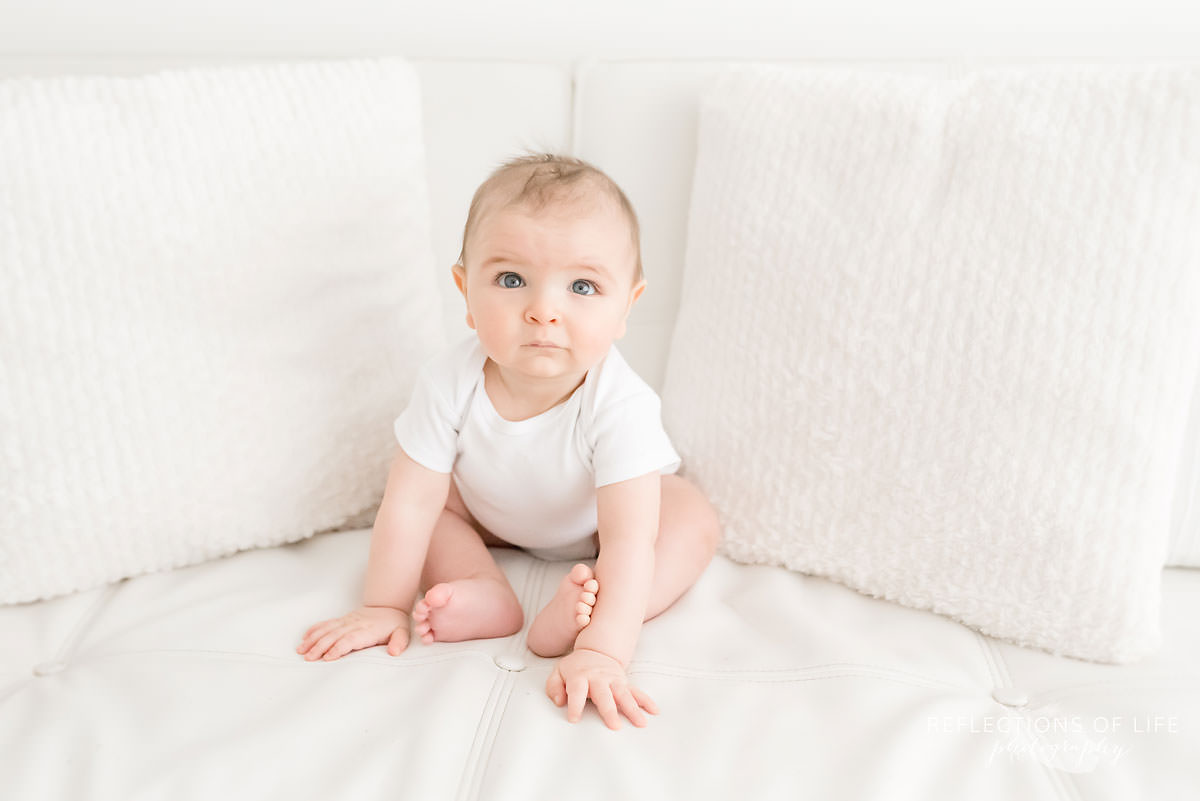 baby tries to sit up on couch in natural light studio