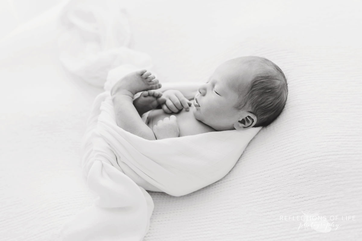 black and white of baby curled up in blanket