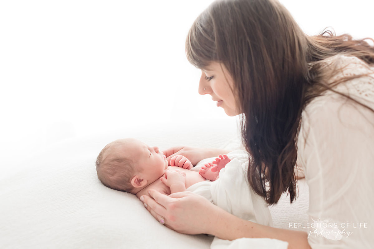 mom holds her baby in natural light studio