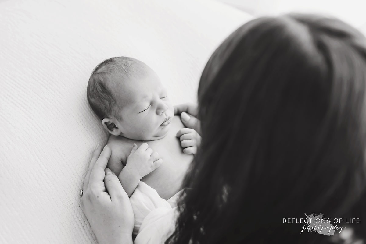 Mother watches over baby while it sleeps in black and white
