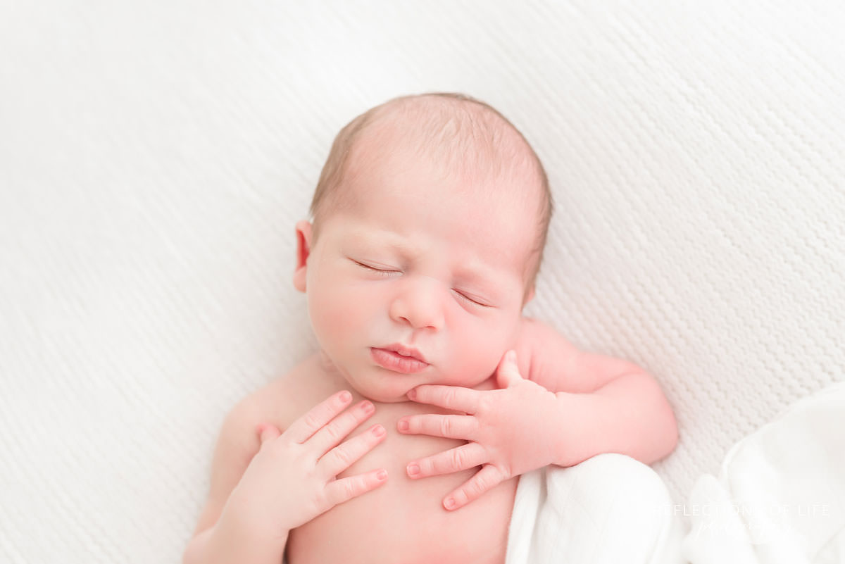 baby holds itself as it sleeps in natural light studio