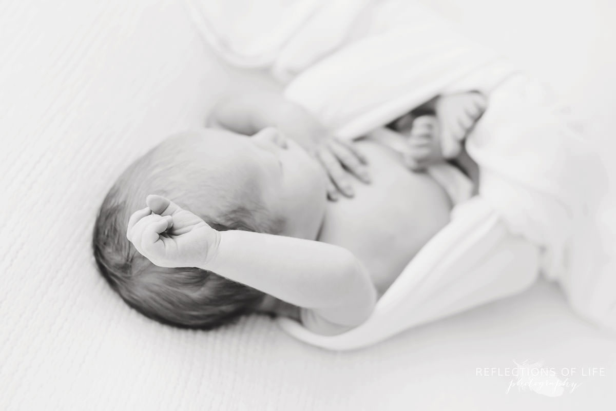 baby sleeping with it's hand in focus in black and white