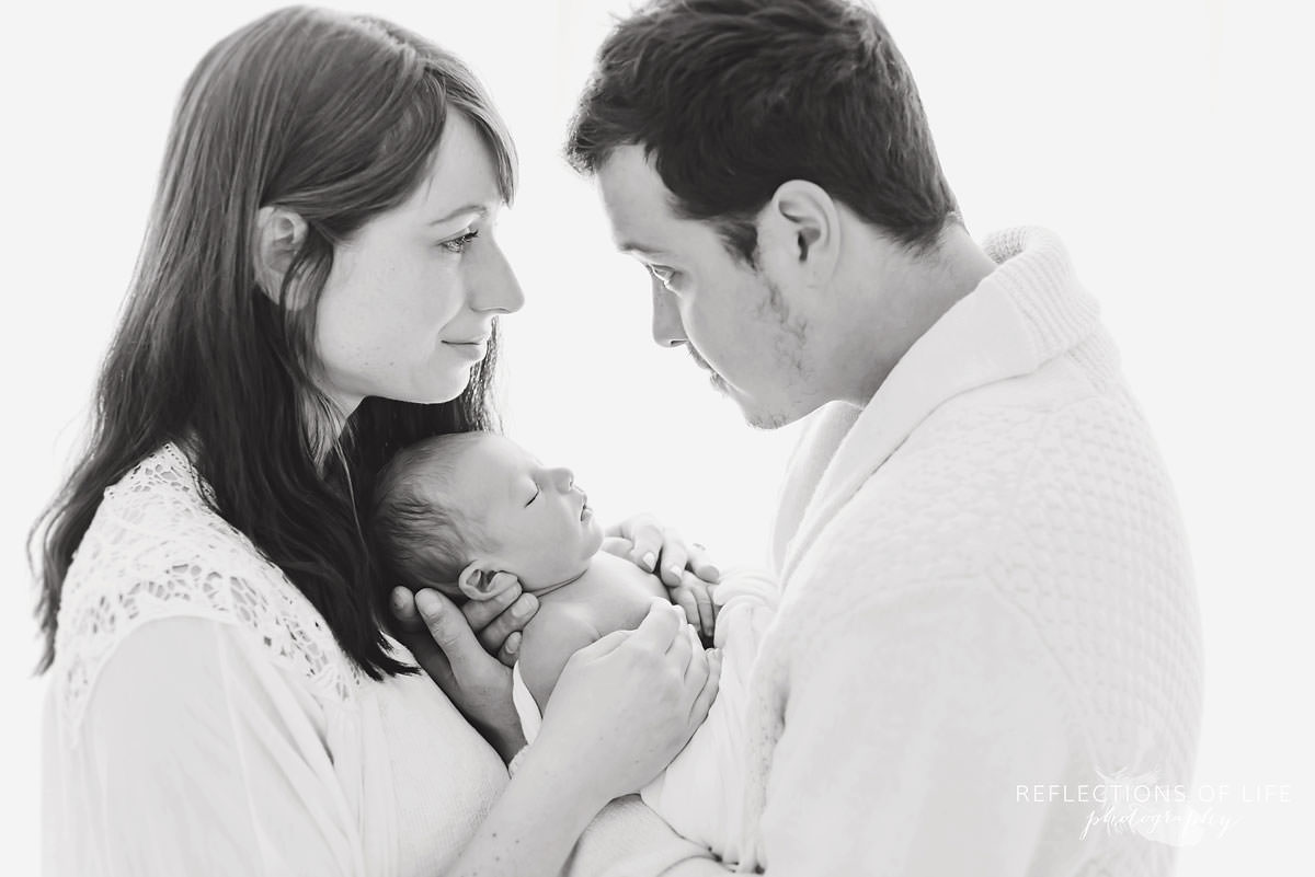 family of three hold their baby in black and white