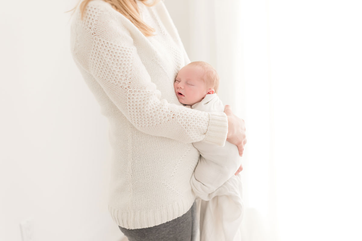 Mother holds her son to her stomach in natural light studio