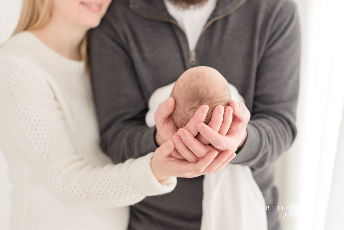 Mom and dad hold their baby's head in ontario