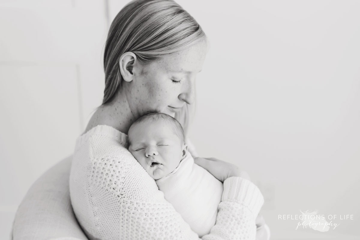 Mother and son cuddle and baby sleeps in black and white
